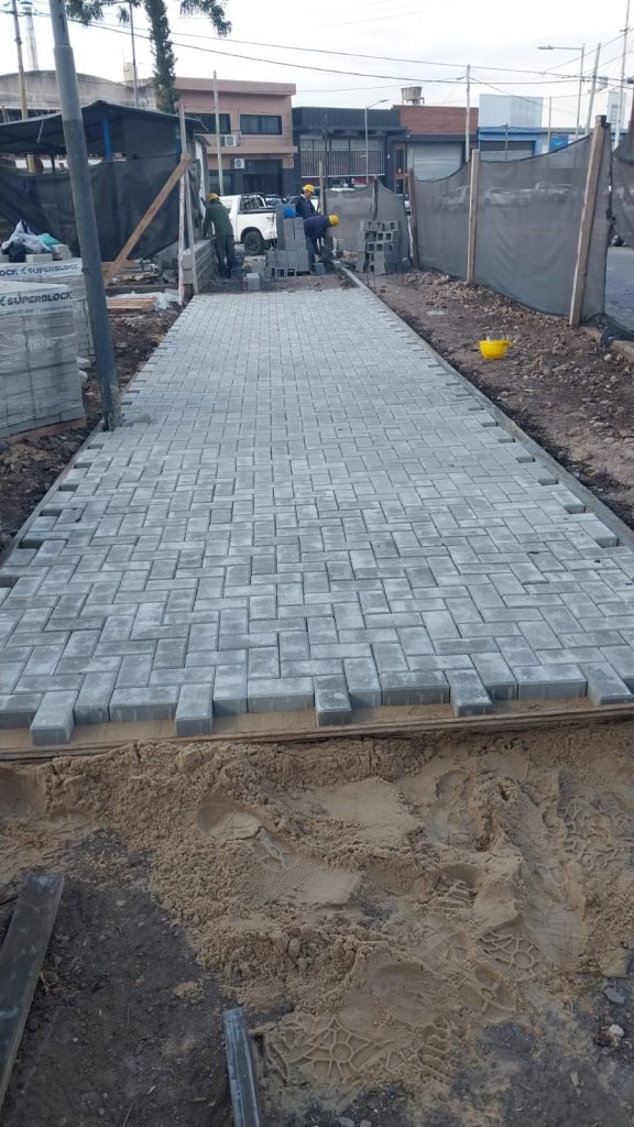 Obra vial en desarrollo con adoquines intertrabados en zona urbana