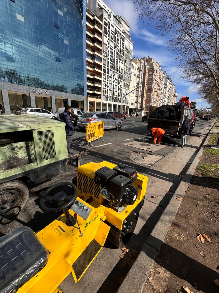 Aplicación de asfalto sobre avenida en obra vial urbana